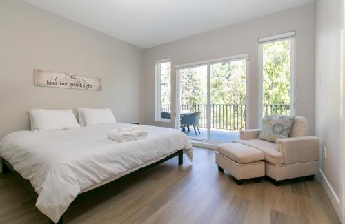 a white bedroom with a bed and a chair at Luxurious Home in Lake Cowichan in Lake Cowichan