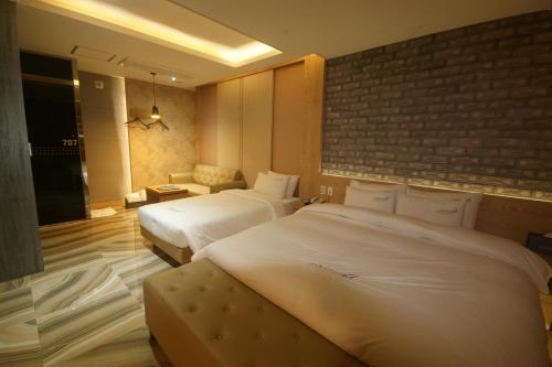 釜山にあるホテル エアポートのレンガの壁のホテルルームで、ベッド2台が備わります。