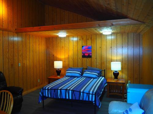 a bedroom with a bed with blue pillows and two lamps at Cavalier Cottage - Private Lakefront w Kayaks! in Honor