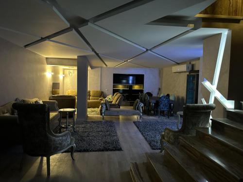 sala de estar con sofá, sillas y TV en Trio villa with falls in compound فلا بحديقة كبيره وشلالات صناعية en Sheikh Zayed