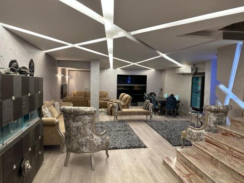ein Wohnzimmer mit einem Sofa, Stühlen und einem TV in der Unterkunft Trio villa with falls in compound فلا بحديقة كبيره وشلالات صناعية in Sheikh Zayed