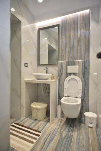 uma casa de banho com um WC, um lavatório e um espelho. em Tirana Central Apartments em Tirana