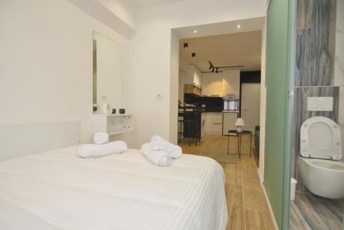 um quarto branco com uma banheira e uma cama com toalhas em Tirana Central Apartments em Tirana