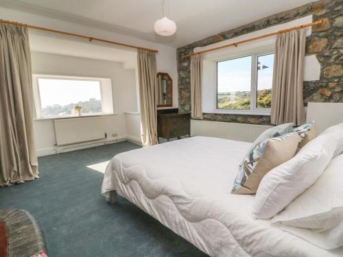 a bedroom with a large bed and two windows at Penmarth House in Helston