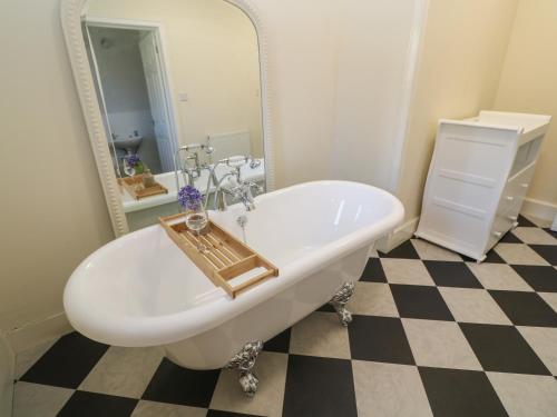 a bathroom with a large mirror and a tub at Penmarth House in Helston
