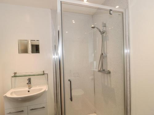 a bathroom with a shower and a sink at Pebbles Foxglove Way in Bridport