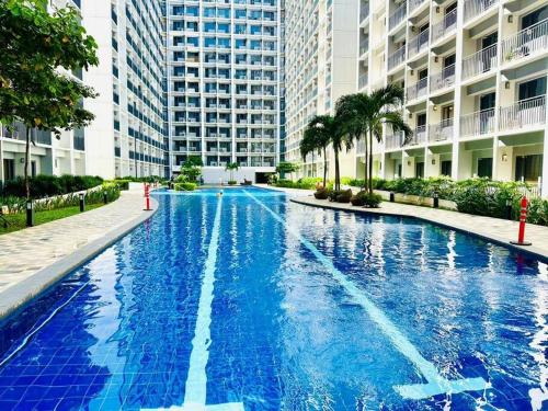a large blue swimming pool with tall buildings at Simple but cozy 1BR Shore 2 MOA in Manila