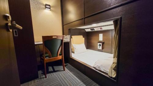 a small room with a bed and a chair at Hotel Palms Tenmonkan in Kagoshima