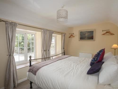 ein Schlafzimmer mit großem Bett und Fenster in der Unterkunft Frongoch Cottage in Pentraeth