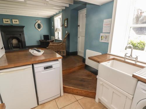 a kitchen with white cabinets and a sink and a fireplace at Patty's Cottage in Haverfordwest