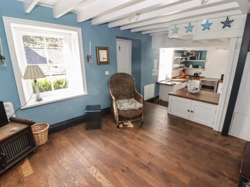 a living room with blue walls and a chair and a window at Patty's Cottage in Haverfordwest