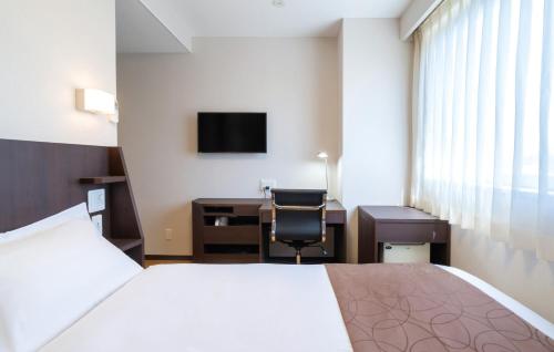 a hotel room with a bed and a desk at Hotel Katsuyama Premiere in Matsuyama