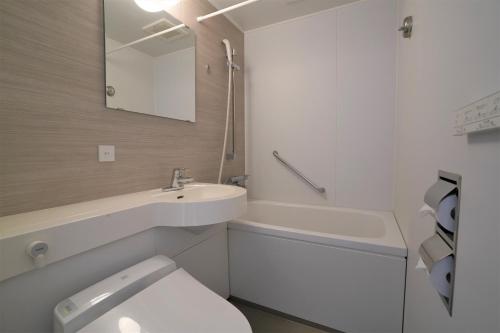 a bathroom with a toilet and a sink and a tub at Hotel Katsuyama Premiere in Matsuyama