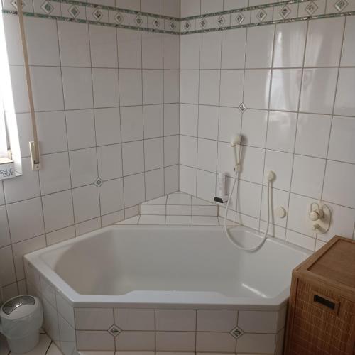 a white tub in a bathroom with a telephone at Ferienwohnung Gogelhopf EG in Unterschneidheim