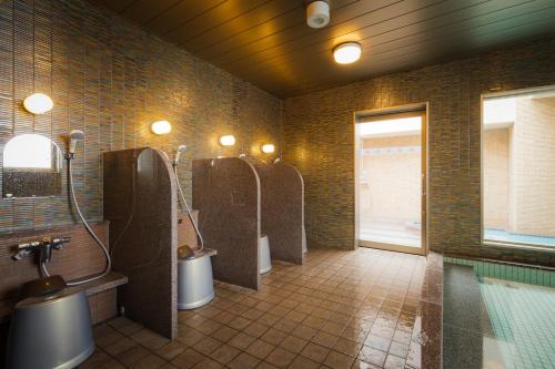 Baño con 3 urinarios y 2 lavabos en Hotel Katsuyama Premiere en Matsuyama