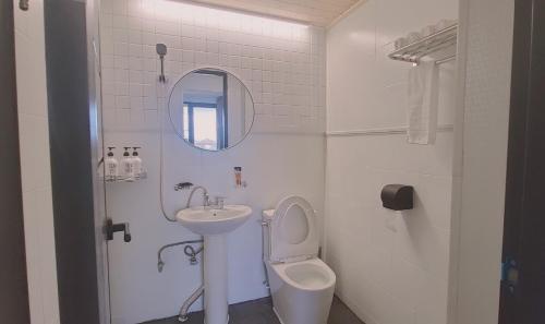 a white bathroom with a sink and a toilet at Jeju Soroan Pension in Seogwipo