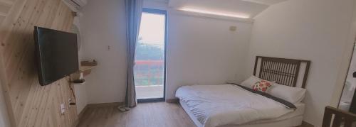 a bedroom with a bed and a large window at Jeju Soroan Pension in Seogwipo