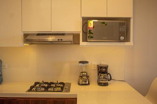 a kitchen with a stove and a microwave at NEW Terra Condo w/ Infinity Pool in Cabo San Lucas