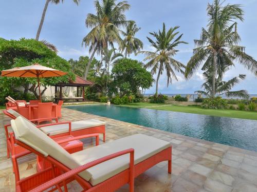 a resort pool with chairs and an umbrella at Villa Singkenken in Kubutambahan