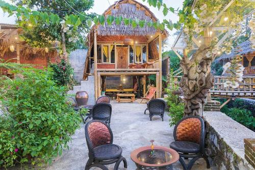 a patio with chairs and a table and a house at Onong's Homestay & Cafe in Tomohon
