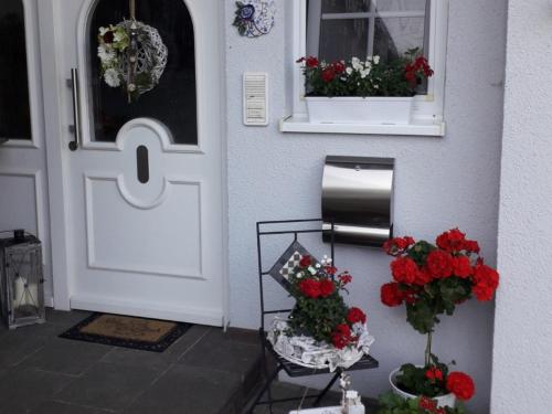 a white door with red flowers and a window at Ferienwohnung Gogelhopf EG in Unterschneidheim