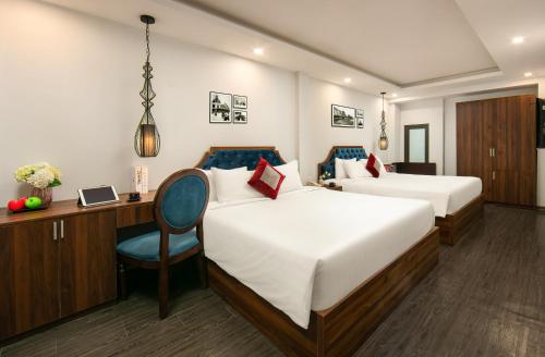 a hotel room with two beds and a desk at La Renta Premier Hotel & Spa Hanoi in Hanoi