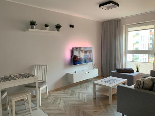 una sala de estar blanca con TV en la pared en Apart 89A Angielska Grobla 5 - Gdańsk Śródmieście, en Gdansk