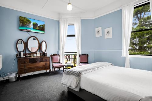 a bedroom with blue walls and a bed and mirrors at Bischoff Hotel in Waratah
