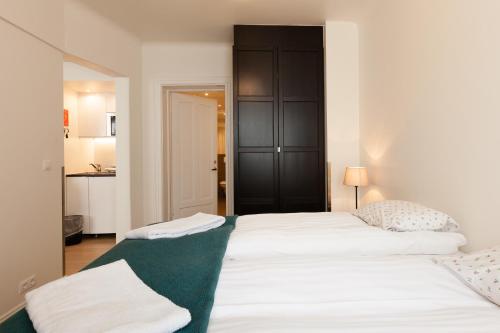 two white beds in a room with a black cabinet at Guesthouse Galtafell in Reykjavík