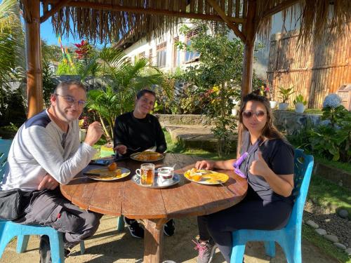 a group of people sitting around a wooden table at Mahoni Guest House in Kelimutu