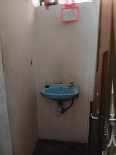 a bathroom with a blue sink on a white wall at Chambre agréable dans un quartier résidentiel in Port Louis