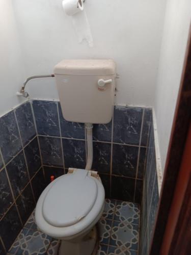 a white toilet in a bathroom with blue tiles at Chambre agréable dans un quartier résidentiel in Port Louis