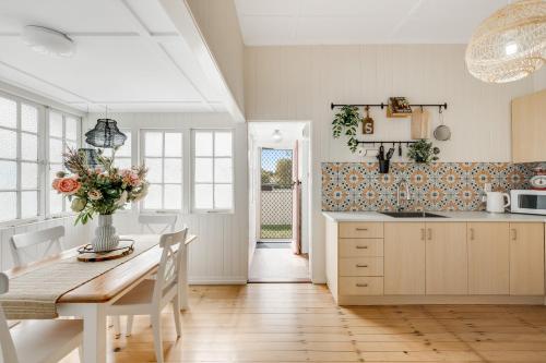 a kitchen with a table with a vase of flowers on it at Cherry Tree Cottage! CBD Magic! in Toowoomba