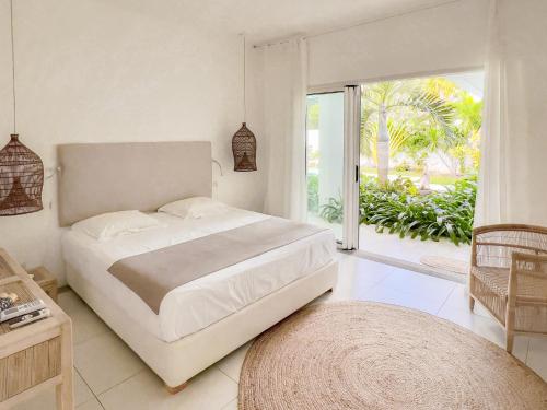 a white bedroom with a bed and a large window at Villa White Horizon by Sealodge in Pointe aux Canonniers