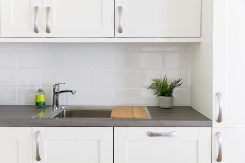 a kitchen with white cabinets and a sink at The Stables in Chichester