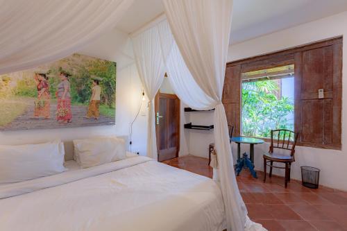 a bedroom with a white bed and a window at Villa Bumi - Playful & Quirky 3BR Villa Near Seminyak, a Unique Getaway in Kerobokan