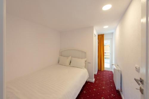 a white bed in a room with a red carpet at Casa Pădurarului in Holbav