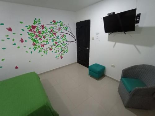 um quarto com uma televisão e um mural de árvore na parede em Hostal Casa del Sol em Santa Marta