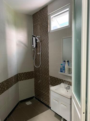 uma casa de banho com um chuveiro e um lavatório. em Ortega Villa em Kuching