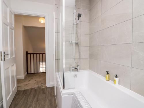 a white bathroom with a tub and a shower at Ramblers Rest in Sedbergh