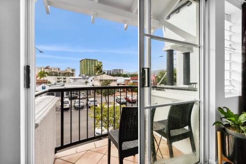 a balcony with two chairs and a view of a city at Villa Vaucluse Apartments in Cairns