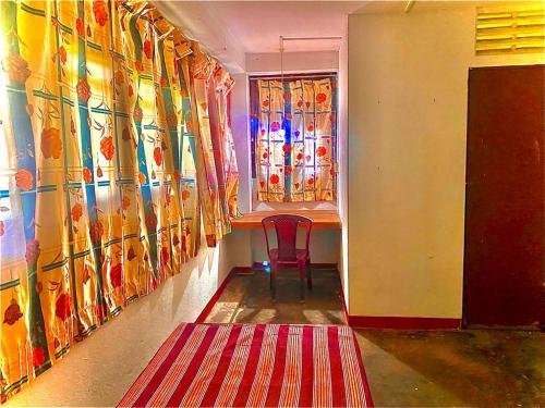 a room with a red rug and a table with a window at Coca Cola Hostel Malabe in Malabe