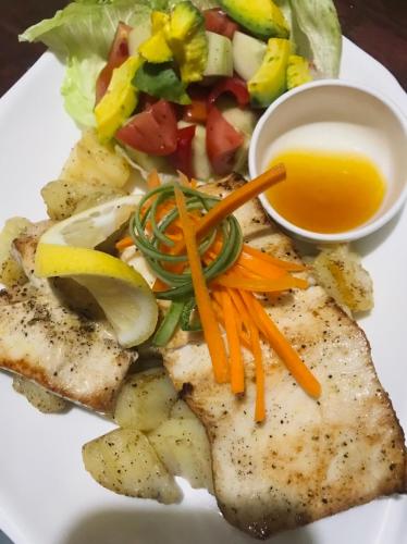 a plate of fish with vegetables and a salad at Chekesh Casa in Siquijor