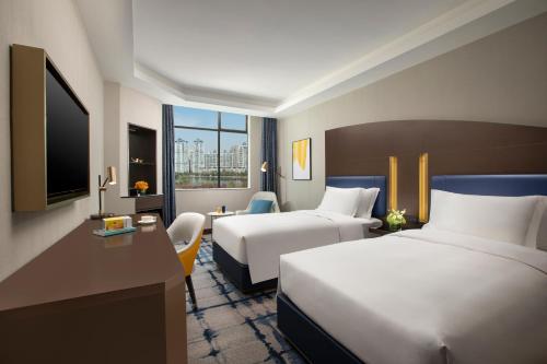 a hotel room with two beds and a television at voco Wuhan Xinhua by IHG in Wuhan