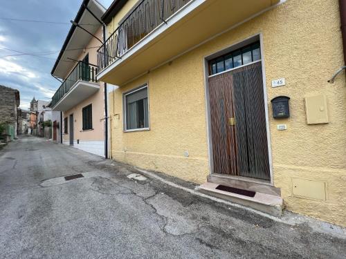 um edifício amarelo com uma porta ao lado de uma rua em Il mondo di Leo em Tocco da Casauria