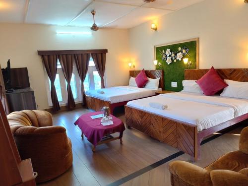 a room with two beds and a couch and chairs at Whispering Winds Resort in Dharamshala