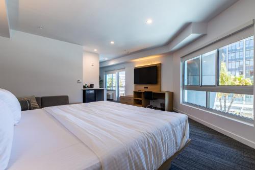 a bedroom with a large bed and a large window at Hotel Mai Downtown Long Beach in Long Beach