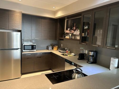 Luxury accomodation in West Vancouver في فانكوفر الغربية: مطبخ مع دواليب خشبية وثلاجة حديد قابلة للصدأ