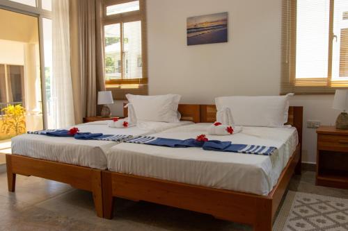 ein Schlafzimmer mit einem großen Bett mit roten Blumen darauf in der Unterkunft Macmillan's Holiday Villas in Grand'Anse Praslin