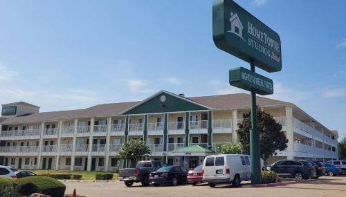 a street sign in front of a large building at HomeTowne Studios by Red Roof Dallas - Irving in Irving